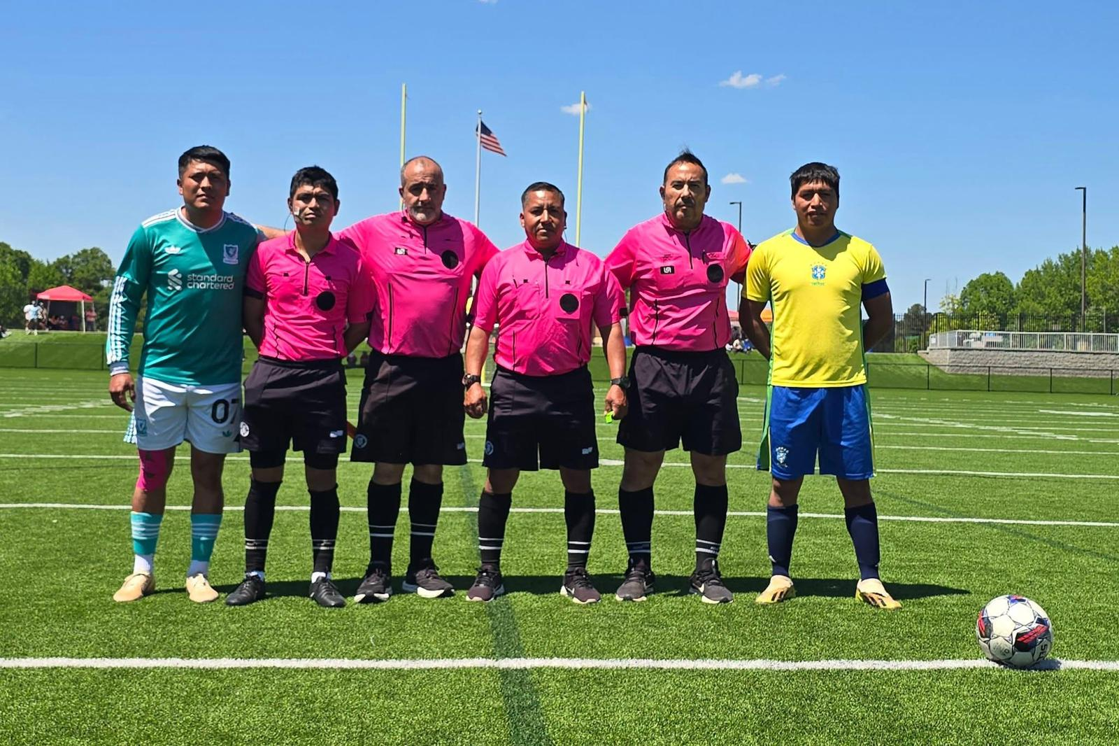 Match captains and referees line up at midfield before kickoff at Odis Spencer Stadium